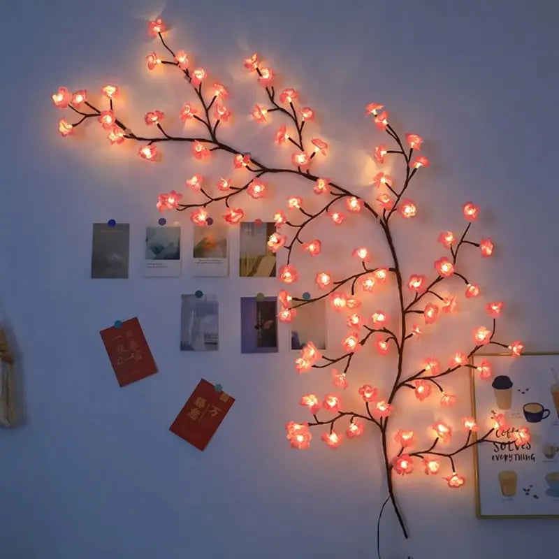 Decorative LED branch with pink lights on a wall with pinned photos and notes.