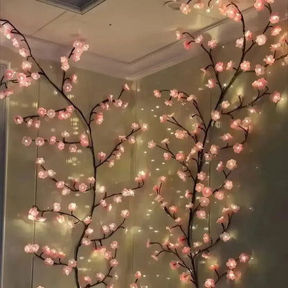 Decorative LED cherry blossom branches with pink lights against a neutral wall.