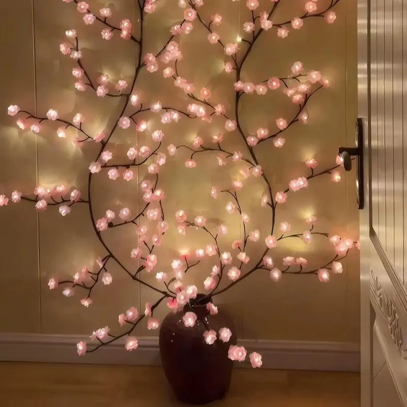 Decorative branch with pink lights in a vase against a neutral wall.
